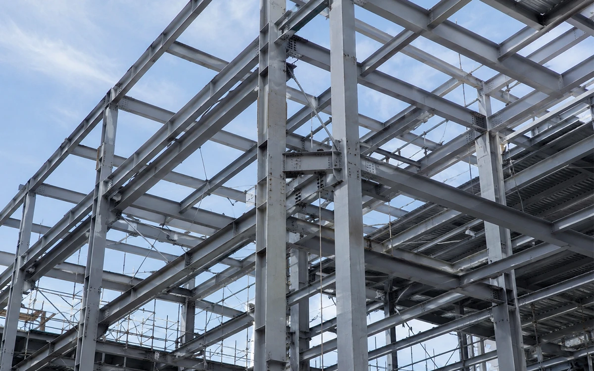 Construction workers performing elevated steel and structural work high above an active jobsite with fall hazards and exposed frameworks