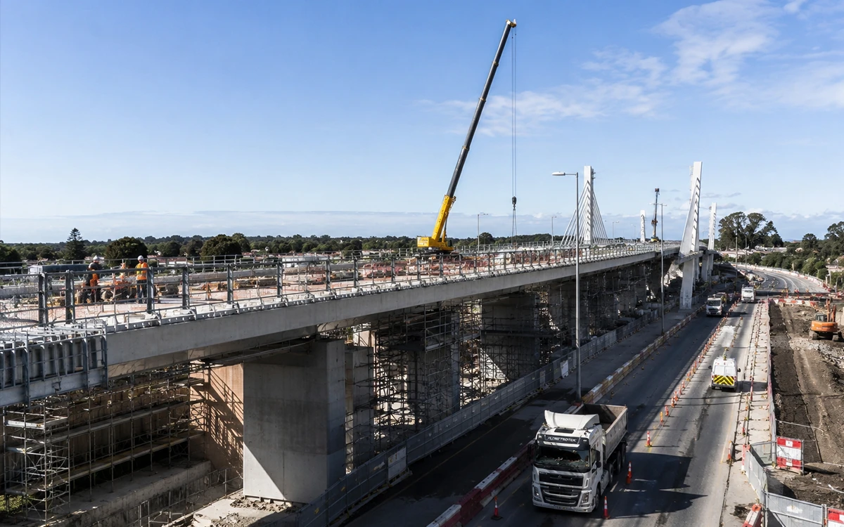 Road and bridge construction crews working around heavy equipment and active infrastructure project zones
